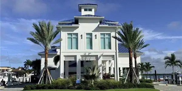 Image 4: White exterior with a blue metal roof, prominent cupola, and mature palm trees