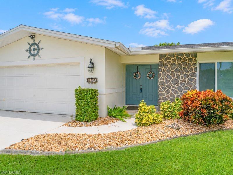 Image 4: Stucco exterior with a two-car garage, stone facade entryway, and a double teal front door