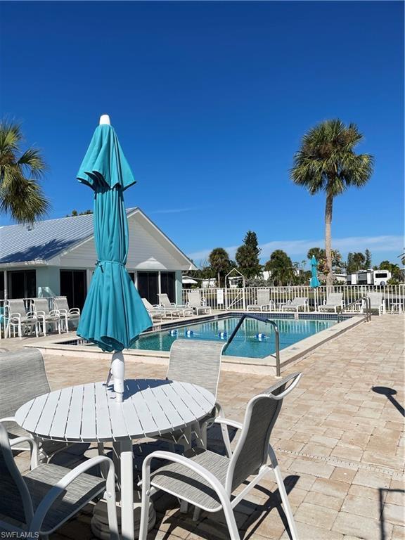 Image 3: Community pool with a patio area and outdoor dining area