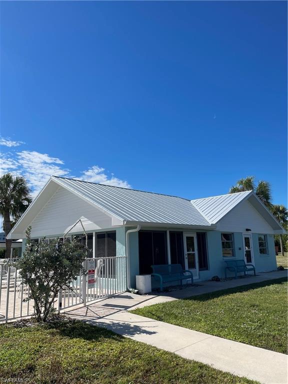 Image 2: Ranch-style home with a metal roof, a front lawn, and covered porch