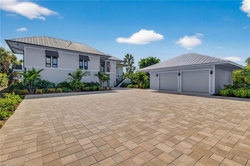 Image 3: View of front facade with a garage, a metal roof, decorative driveway, and an outdoor structure