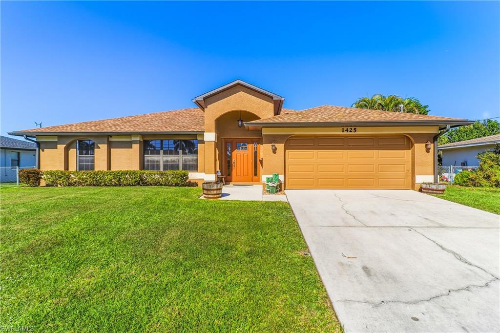Image 3: View of front of house with an attached garage, stucco siding, driveway, a front lawn, and a shingled roof