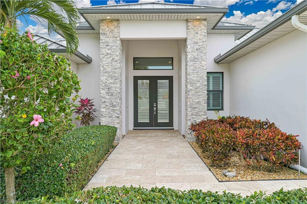 Image 2: View of exterior entry with stucco siding, stone siding, and french doors