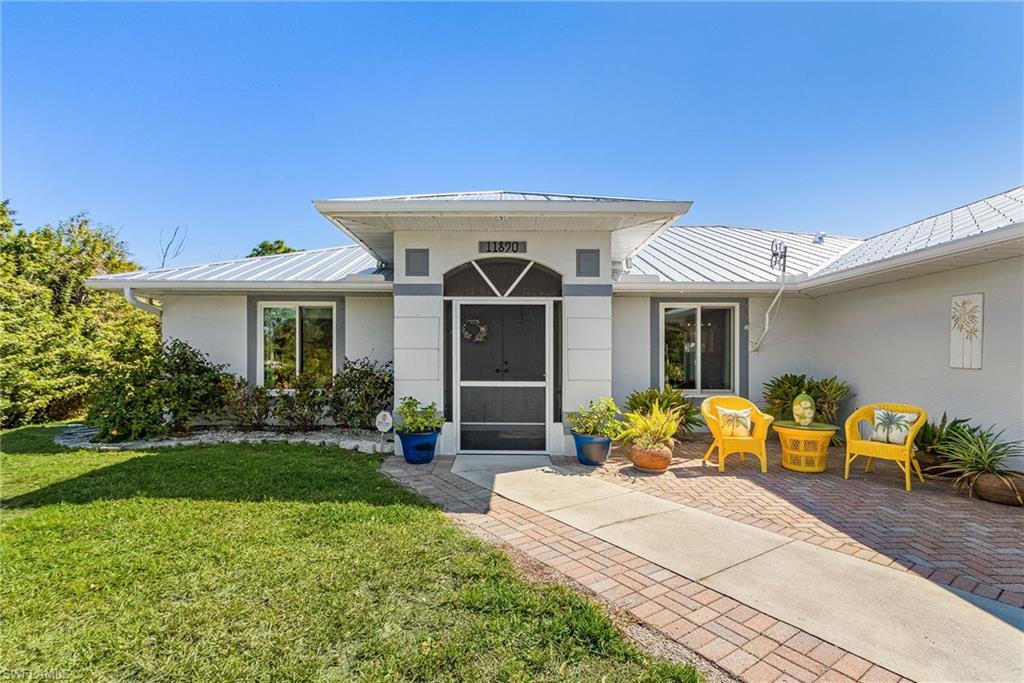 Image 2: Doorway to property featuring a standing seam roof, a yard, and stucco siding
