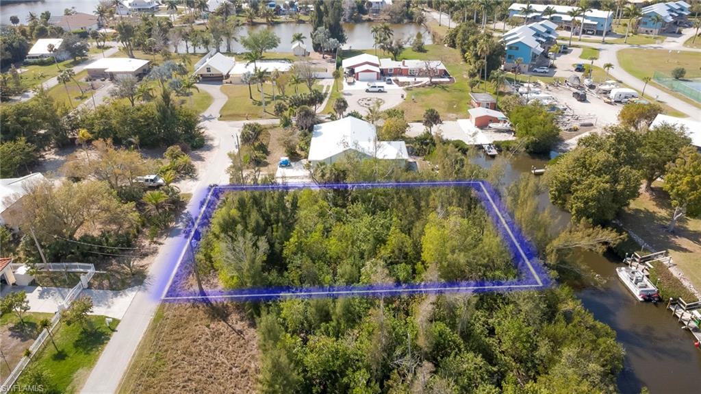 Image 3: Aerial view of residential area featuring property parcel outlined and a large body of water