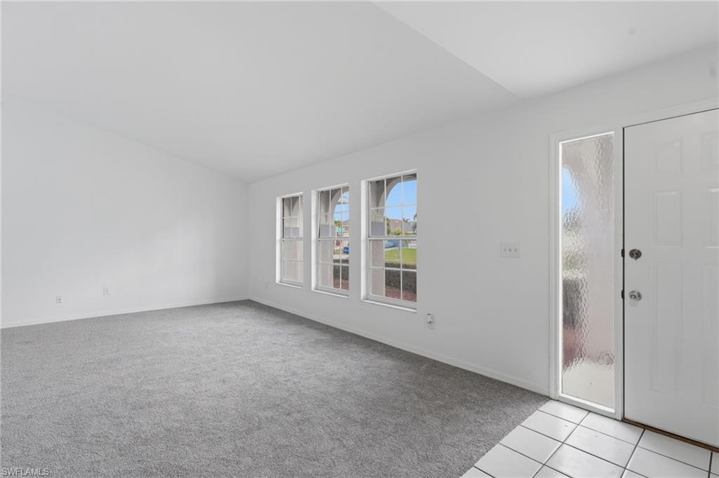 Image 4: Carpeted living area with white walls and multiple windows