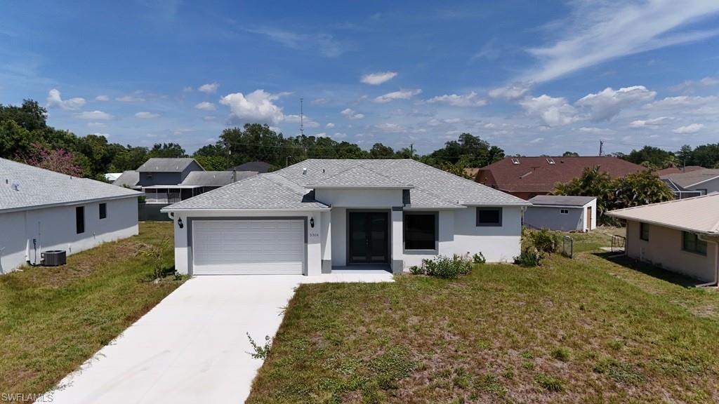 Image 2: Modern single-story residence featuring a light-colored exterior with dark trim accents