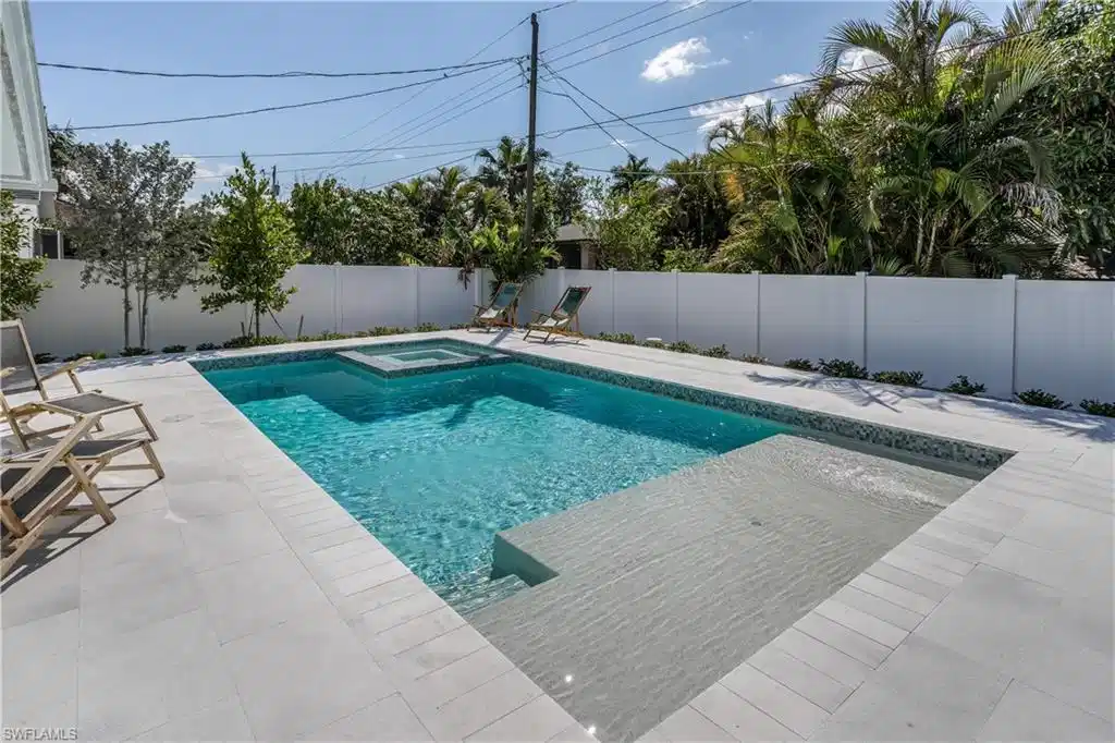 Image 1: View of swimming pool featuring a patio area, a pool with connected hot tub, and a fenced backyard
