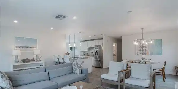 Image 3: Living area with a chandelier, wood finished floors, visible vents, and recessed lighting