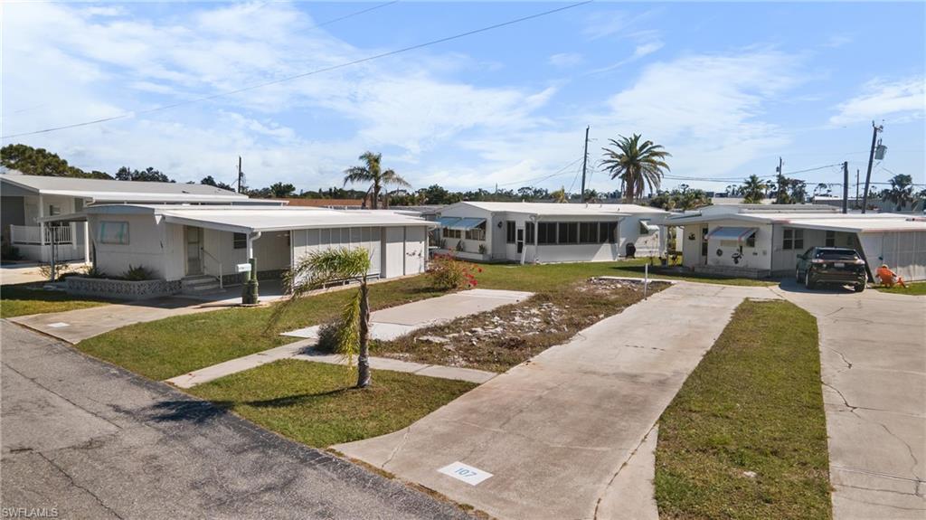 Image 1: White exterior featuring a covered entry porch, an attached carport, a concrete driveway, and a manicured lawn