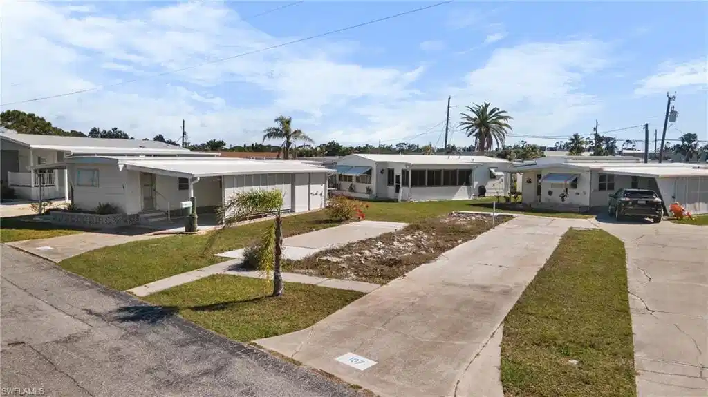 Image 1: White exterior featuring a covered entry porch, an attached carport, a concrete driveway, and a manicured lawn