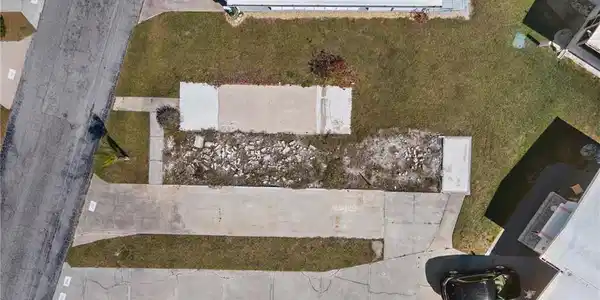 Image 2: Expansive lot featuring concrete pads, an extended driveway, and a partially cleared area
