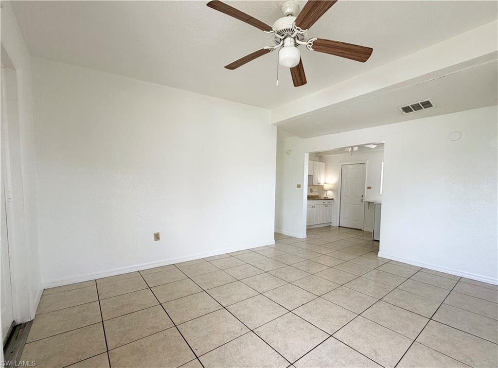 Image 4: Spacious room featuring tile flooring, a ceiling fan with wood-finish blades, and white walls