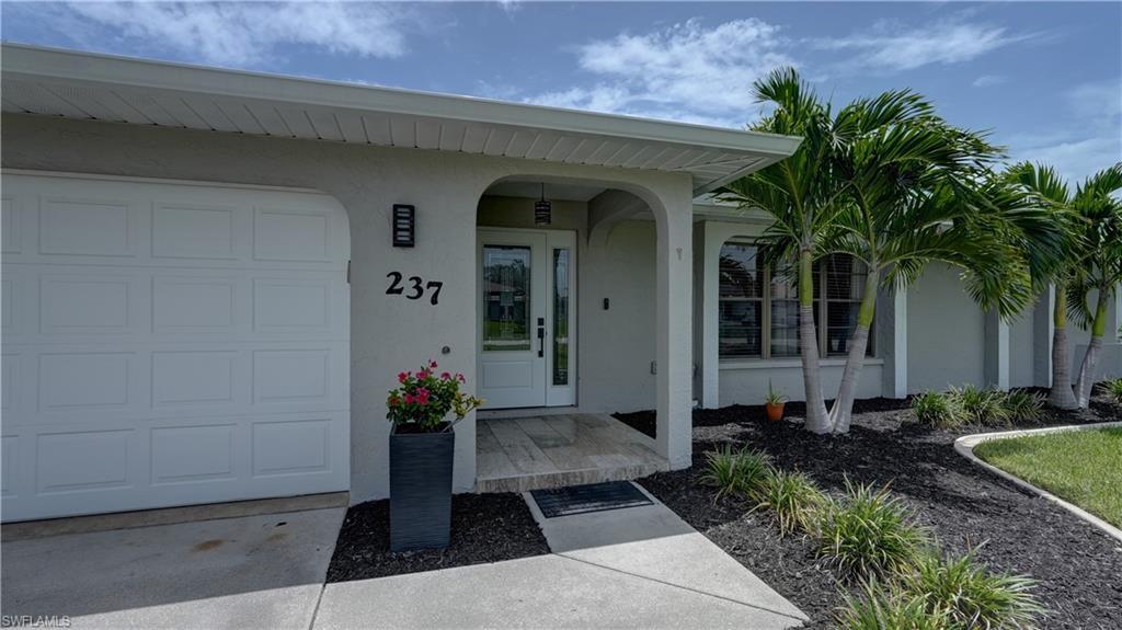 Image 3: Stucco exterior featuring a two-car garage, double-door entry, and a covered entryway