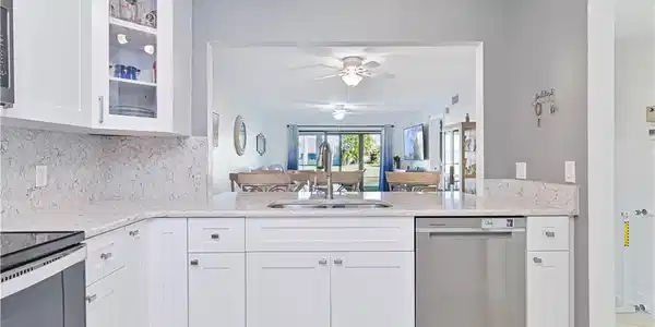 Image 3: Kitchen with white cabinets, light stone counters, stainless steel appliances, and glass insert cabinets