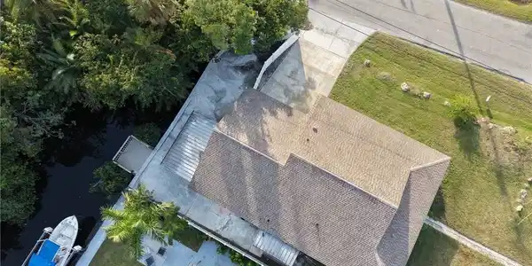 Image 2: Waterfront property featuring a spacious residence with a gabled roof and multiple roof planes, situated on expansive grounds with mature landscaping, manicured lawn, and direct water access with boat dock