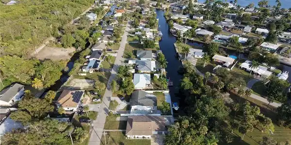 Image 3: Aerial view showcasing this waterfront community featuring mature landscaping, private canal access, and tree-lined streets throughout the neighborhood