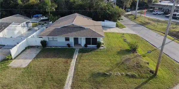 Image 4: Spacious single-story residence with a pitched roof and modern architectural lines, situated on an expansive lot featuring mature landscaping and established trees