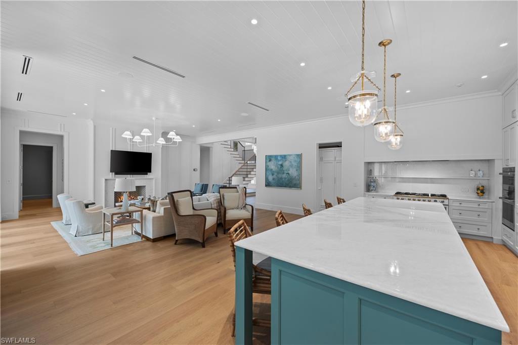 Image 3: Kitchen with light hardwood / wood-style floors, crown molding, white cabinetry, and pendant lighting