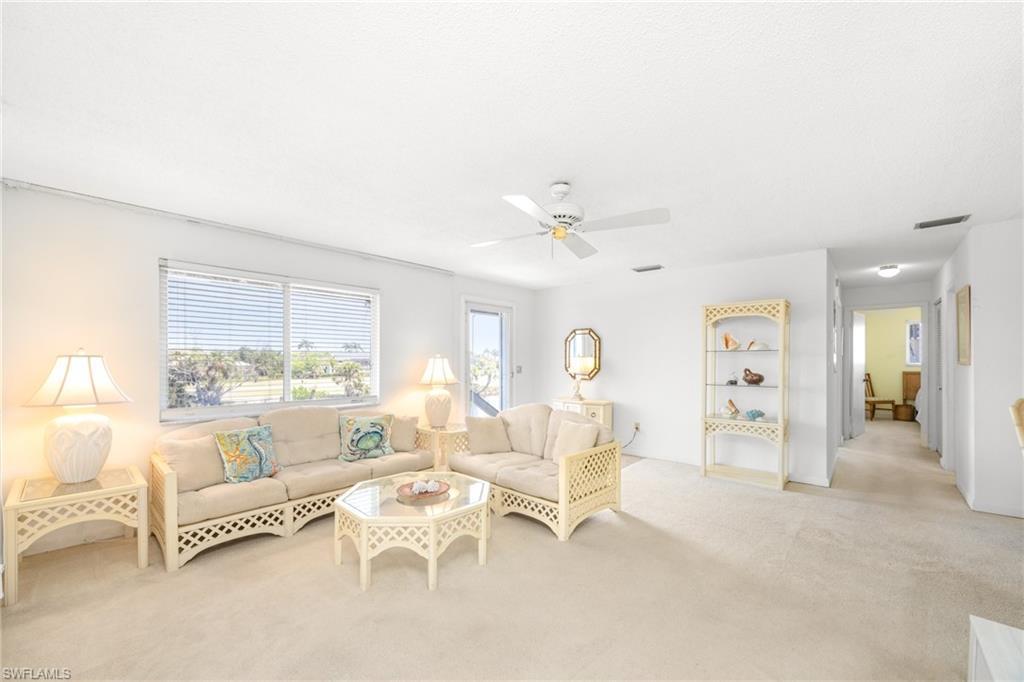 Image 2: Living area with a ceiling fan, visible vents, and carpet