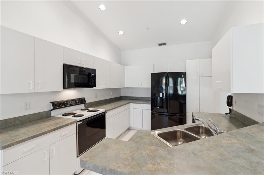 Image 4: Kitchen featuring black appliances, a sink, lofted ceiling, recessed lighting, and white cabinets