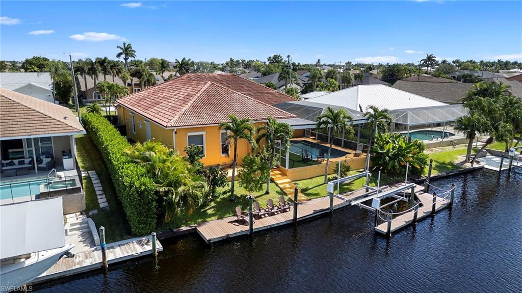Image 4: Dock featuring boat lift, a lanai, a water view, an outdoor pool, and a patio