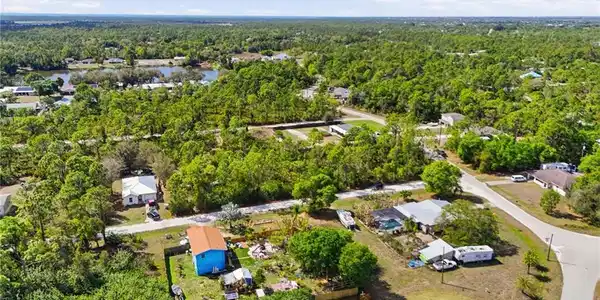 Image 4: Aerial perspective of suburban area with a heavily wooded area and a large body of water