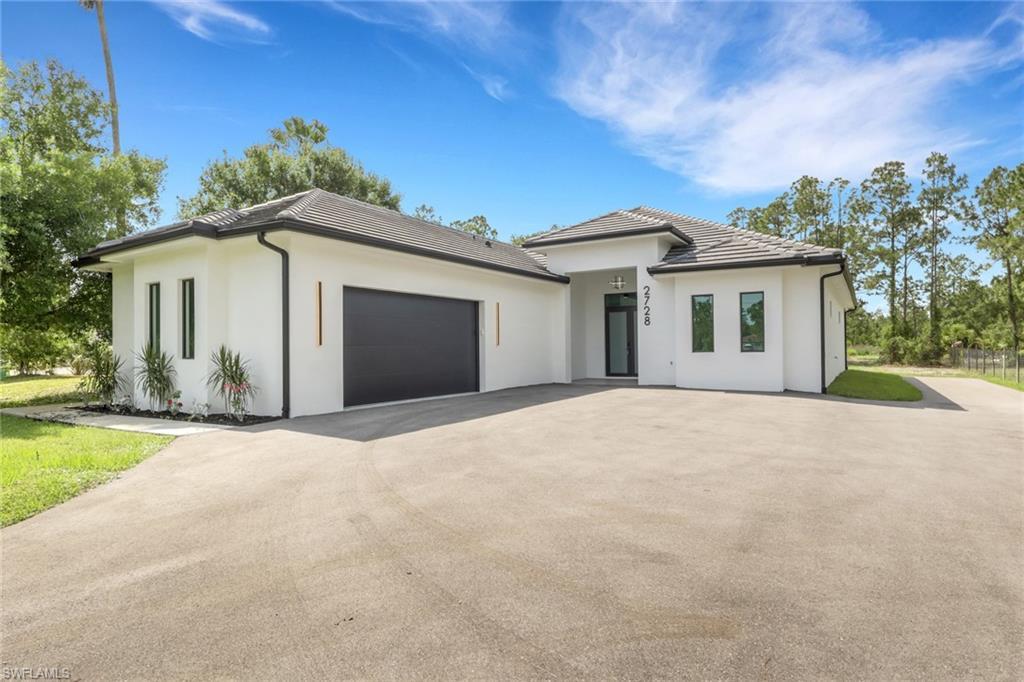 Image 2: Contemporary white stucco exterior with black trim accents and a dark tile roof