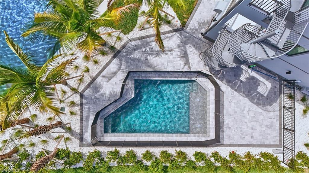 Image 3: Contemporary swimming pool with integrated spa, surrounded by paver patio and white gravel landscaping - Virtually Edited Image