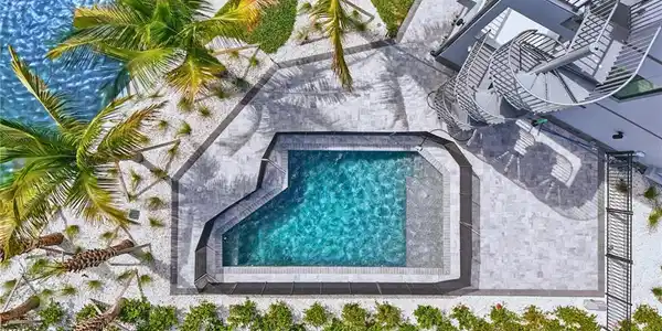 Image 3: Contemporary swimming pool with integrated spa, surrounded by paver patio and white gravel landscaping - Virtually Edited Image