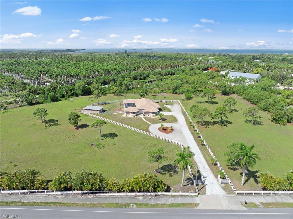 Image 1: Expansive property featuring a circular driveway, white perimeter fencing, and mature palm trees