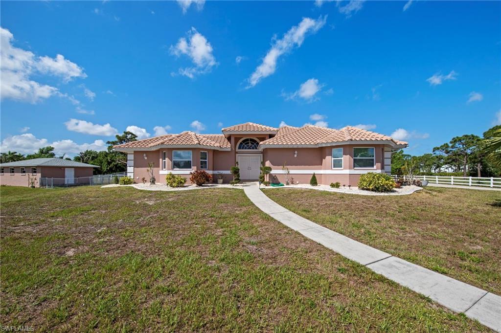 Image 3: Stucco exterior residence featuring a tile roof, arched entryway, and multiple front windows