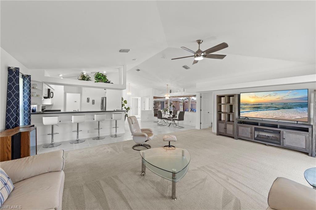 Image 4: Spacious living area featuring vaulted ceilings, ceiling fan, and carpet flooring