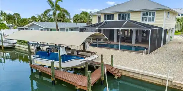Image 2: Dock area with boat lift, screened in pool and Gulf access canal - virtually enhanced