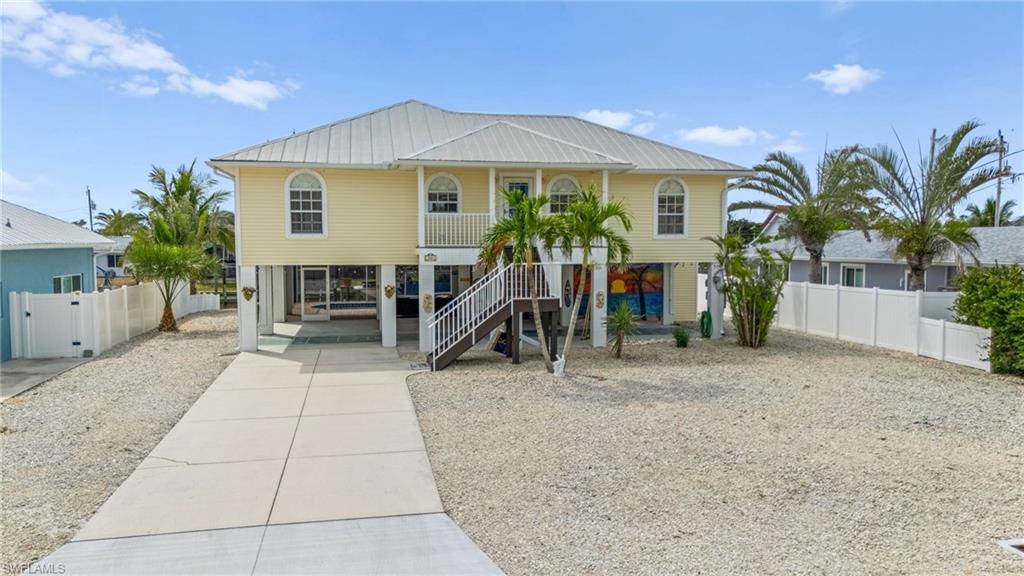 Image 4: Coastal home featuring covered porch, stairway, driveway, metal roof, and a carport-Virtually enhanced