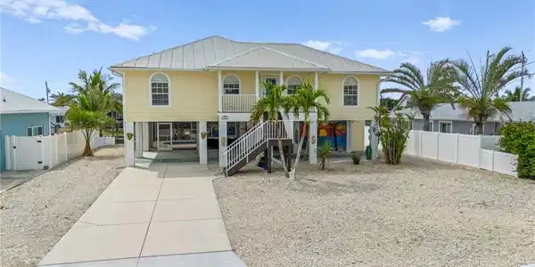 Image 4: Coastal home featuring covered porch, stairway, driveway, metal roof, and a carport-Virtually enhanced
