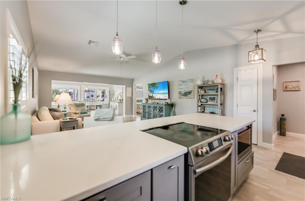 Image 3: Kitchen with appliances with stainless steel finishes, gray cabinetry, a ceiling fan, lofted ceiling, and open floor plan