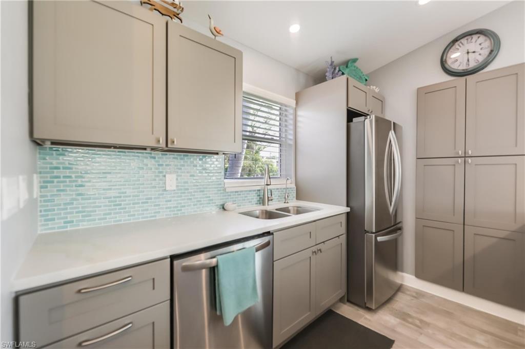 Image 4: Kitchen with appliances with stainless steel finishes, light countertops, light wood finished floors, tasteful backsplash, and gray cabinets