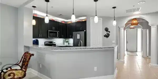 Image 3: Kitchen featuring decorative columns, arched walkways, pendant lighting, a peninsula, and appliances with stainless steel finishes