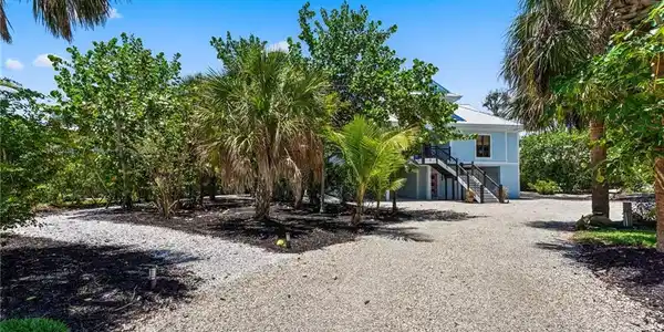 Image 2: View of front of house with stairway, driveway, and a metal roof