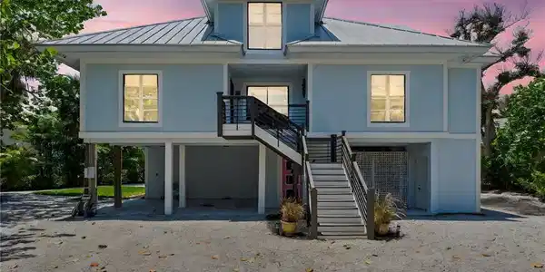 Image 3: View of front facade with a metal roof, a carport, stairway, and driveway