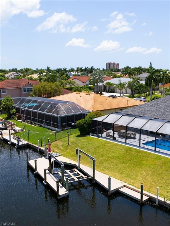Image 2: Dock with glass enclosure, a yard, a water view, boat lift, and a sunroom