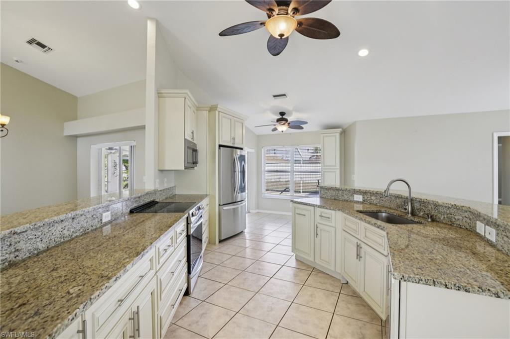 Image 3: Kitchen with stainless steel appliances, light stone counters, ceiling fan, white cabinetry, and recessed lighting