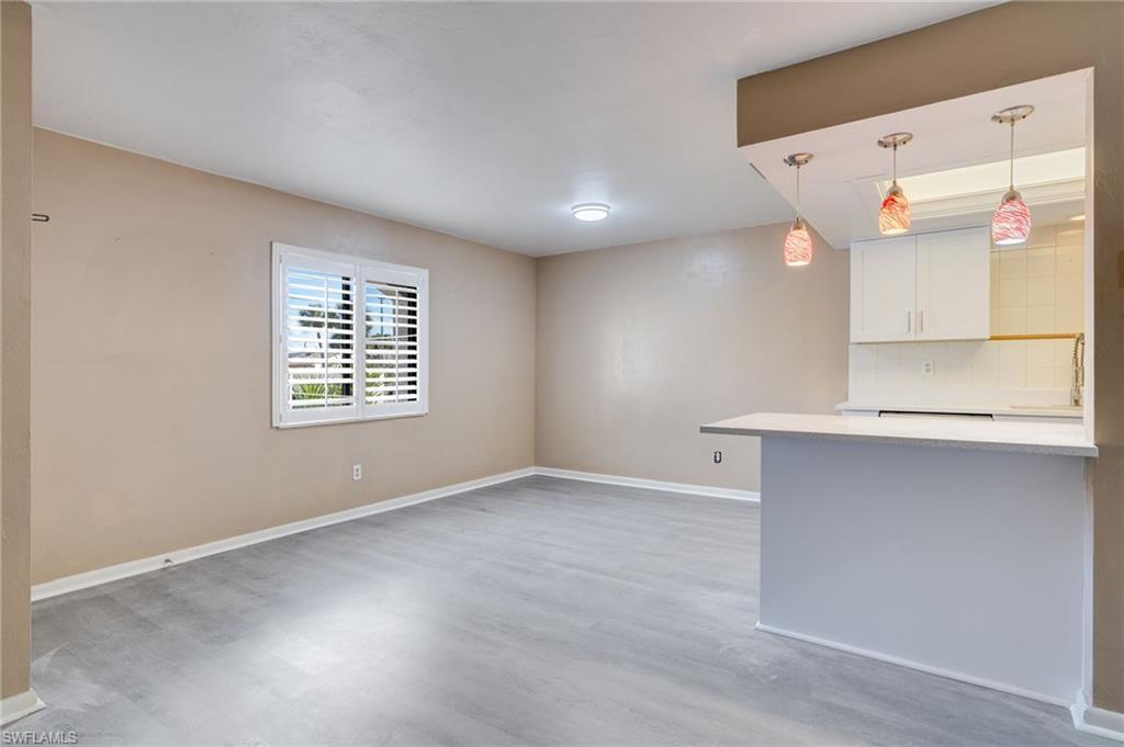 Image 2: Kitchen featuring white cabinetry, hanging light fixtures, light wood-style flooring, and backsplash