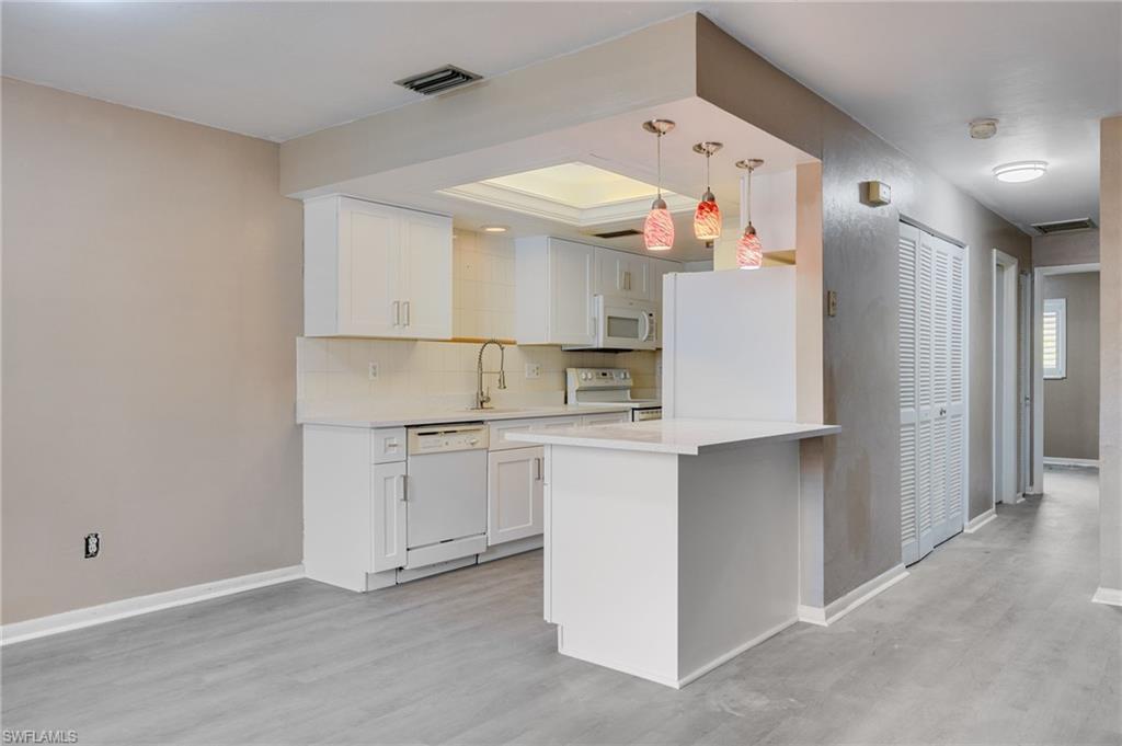 Image 4: Kitchen featuring white cabinetry, white appliances, pendant lighting, light wood-style flooring, and a peninsula