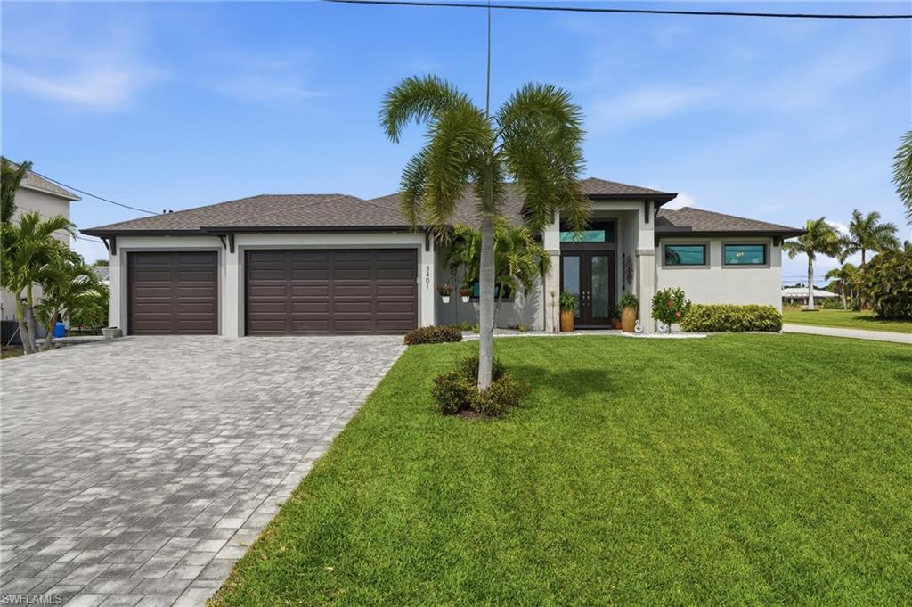 Image 2: Prairie-style home with decorative driveway, an attached garage, double glass doors, a front yard, and stucco siding