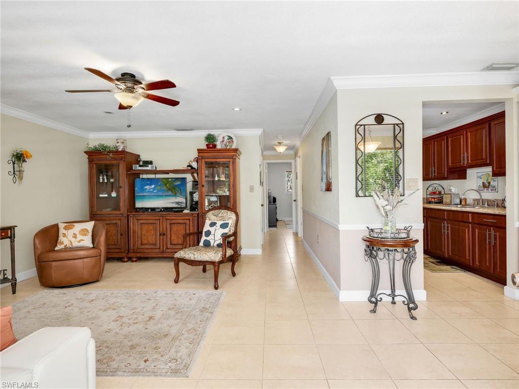 Image 2: Living room featuring light tile patterned floors, ceiling fan, and ornamental molding