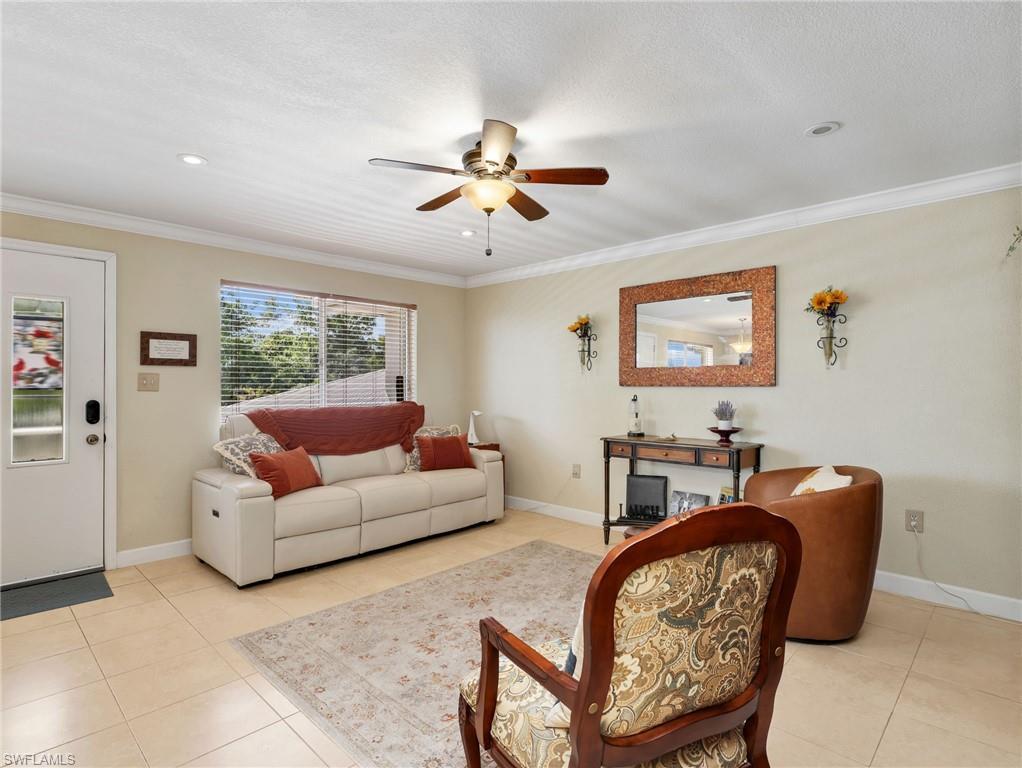 Image 4: Living area with light tile patterned flooring, ceiling fan, and ornamental molding