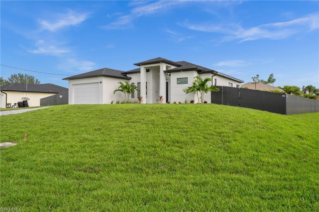 Image 1: Contemporary stucco exterior featuring a grand entryway with double glass doors, a recessed porch, a paver walkway, and mature tropical landscaping