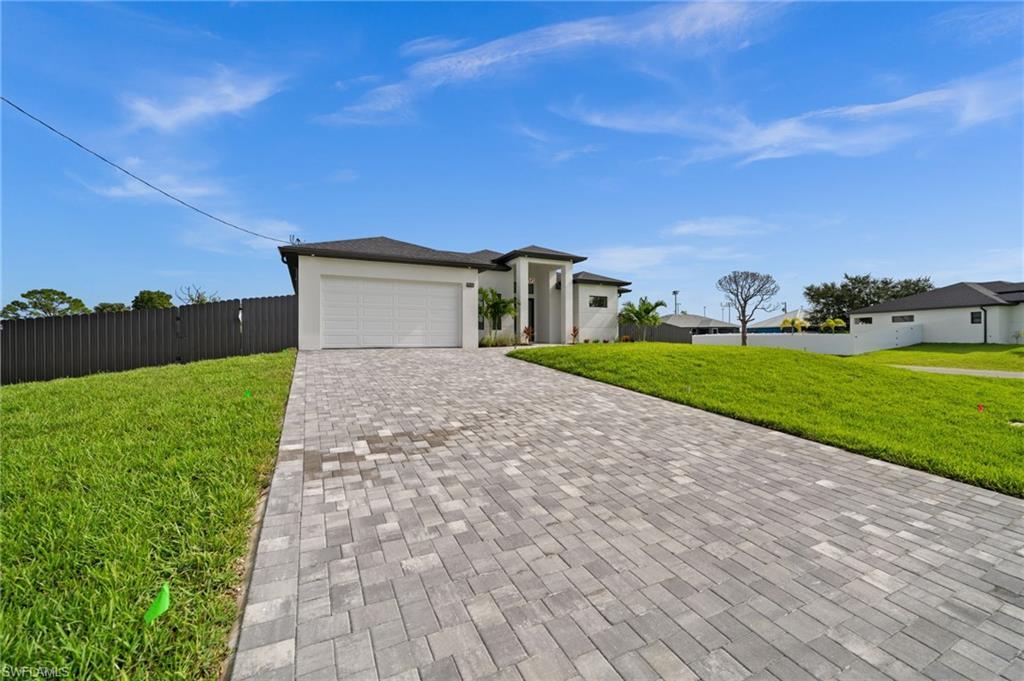 Image 3: Single-story residence featuring a dark shingle roof, white stucco exterior, and a grey paver driveway